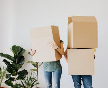 couple carrying cardboard boxes in living room