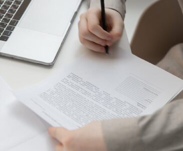 faceless male worker with paper document near laptop on desk