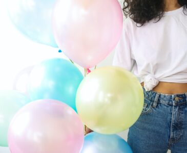 woman in white shirt and blue denim jeans holding balloons