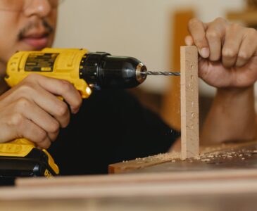 man drilling timber panel with screwdriver on table